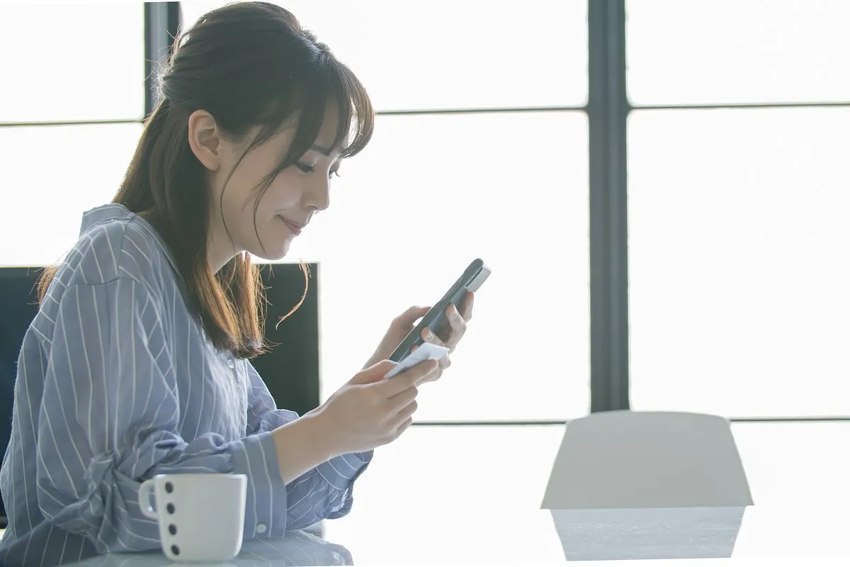 スマホとカードを手に持つ女性