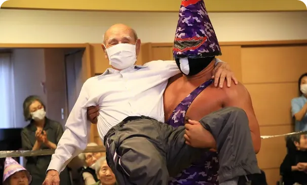 高齢者を抱っこするプロレスラー